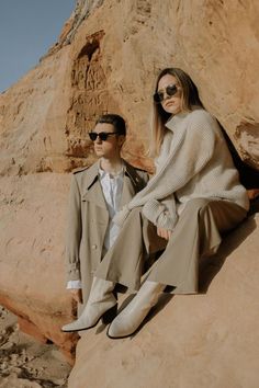 a man and woman sitting on top of a rock in front of a desert landscape