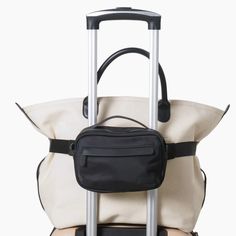 a white and black bag sitting on top of a piece of luggage