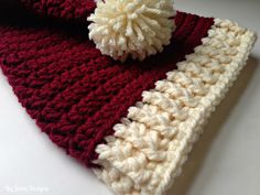 a red and white crocheted hat with a pom - pom