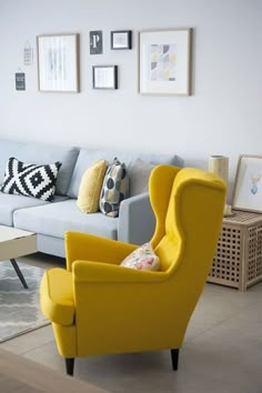 a living room with yellow chairs and pictures on the wall above it's couch