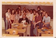 a group of people sitting at desks in front of a chalkboard