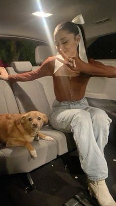 a woman sitting in the back seat of a car next to a dog