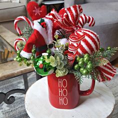 a red coffee cup filled with candy canes and christmas decorations on top of a table