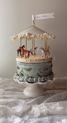 there is a cake with horses on it and an umbrella topper in the shape of a carousel