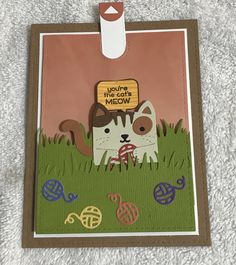 a close up of a card with a cat on the grass and an empty tag attached to it