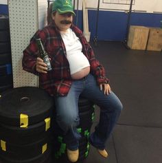 a man with a mustache sitting on top of some barrels and holding a beer bottle