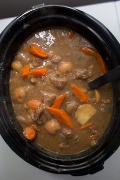 a stew with carrots, potatoes and meat in a crock pot on the stove