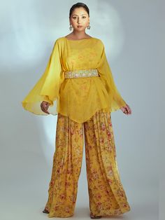 This is a four-piece Yellow Floral Print Kaftan Set from the Suruchi Parakh collection. The yellow embroidered kaftan in organza is paired with floral printed flared pants & bustier. The yellow kaftan has pearl buttis all over. The floral crop top has a back hook opening. The yellow color with pleats, padding and floral print enhances the graceful, kaftan set. The outfit is completed with a floral embroidered broad belt. Organza Kaftan, Kaftan Outfit, Yellow Kaftan, Kaftan Set, Pink Sharara, Embroidered Kaftan, Kaftan Top, Floral Print Pants, Organza Dress