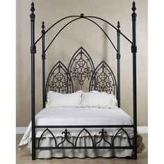 an iron bed frame with white sheets and pillows