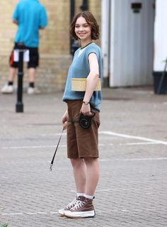 a young woman is standing on the street with her walking stick and smiling at the camera