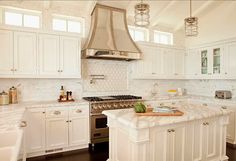 a large kitchen with white cabinets and marble counter tops, along with an island in the middle