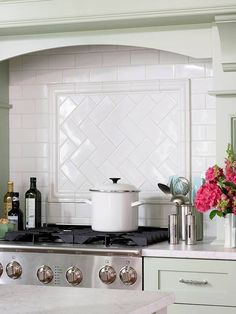 a stove top oven sitting inside of a kitchen next to a vase with flowers on it