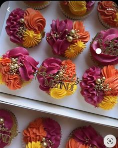 cupcakes decorated with colorful flowers and monogrammed nameplates are on display