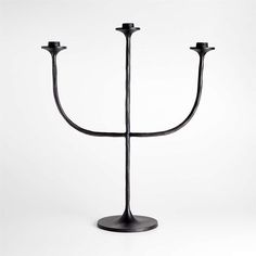 a black metal candle holder with three candles on it's sides and one is turned upside down