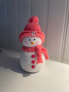 a knitted snowman with a pink hat and scarf