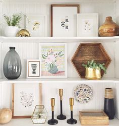 shelves with vases, pictures and other items on them in a white living room