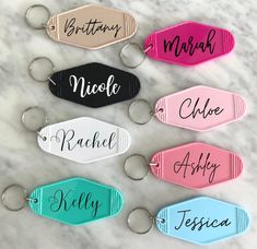 personalized keychains with names on them sitting on a marble countertop in different colors