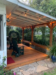 a patio covered in lights and furniture next to a building with a deck on the other side