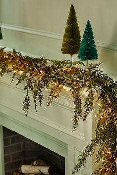 a fireplace mantel decorated with christmas trees and lights