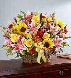 a basket filled with lots of colorful flowers on top of a wooden table next to a book