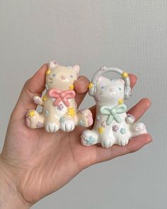 two small figurines in the palm of someone's hand, one with a cat on it