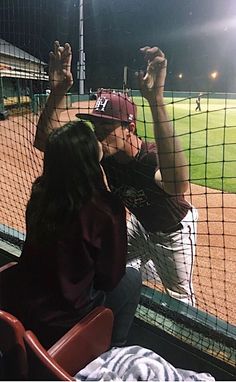 a baseball player sitting in the dugout with his hand up to catch a ball