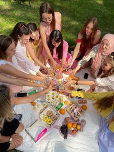 a group of young women standing around a table covered in food