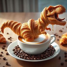 a toy t - rex sitting in a cup of coffee with croissants around it