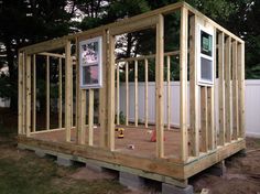 a house being built in the backyard with wood framing around it's walls and windows