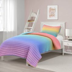 a bed with a rainbow colored comforter and pillows