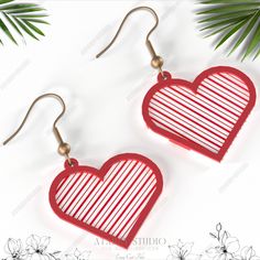 pair of red and white heart shaped earrings with gold earwires hanging from hooks