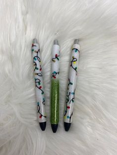 three pens sitting on top of a white fur covered floor with christmas lights painted on them