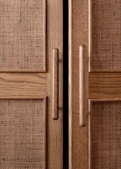 two wooden doors with woven panels and handles on each one side, in front of a black background