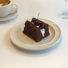 a piece of cake on a white plate next to a cup of coffee