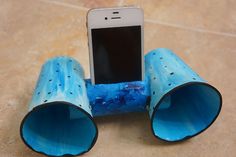 a cell phone is in the middle of three blue pipes on the ground, with one being held up by it's front end