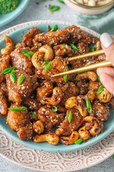 someone holding chopsticks over some food on a plate