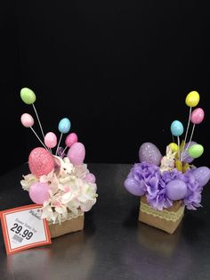 two small vases with flowers and balloons in them sitting on a table next to a price tag