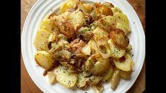 a white plate topped with potatoes covered in seasoning on top of a wooden table