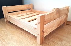 a wooden bed frame sitting on top of a hard wood floor next to a wall