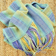 a blue and yellow scarf laying on top of a rug