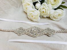 This Art Deco Beaded Wedding Belt is made with tiny silver seed beads, ivory pearls, and different shaped diamante rhinestones. The belt measures 31 inches long and 2.5 inches at it's widest. Set on a 120 inch long white or ivory satin ribbon. Everything is lined in felt so this is sturdy and won't fall apart. Like our Facebook page and receive a 10% discount when you message me before checkout! Everything made by handmade MKE is one of a kind and unique, however, if you would like a different s White Adjustable Wedding Sashes, Adjustable Beaded Bridal Belt For Wedding, Cream Beaded Bridal Accessories For Wedding, Silver Bridal Belt With Pearl Embroidery, Silver Bridal Belt With Pearl Embroidery For Wedding, Wedding Pearl Beaded Bridal Belt, Wedding Bridal Belt Beaded With Pearls, Wedding Bridal Belt With Beaded Pearls, Bride Plus Size