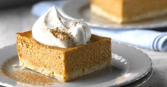 a slice of pumpkin pie with whipped cream on top sits on a plate next to another piece of pie