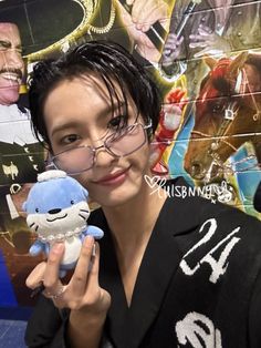 a woman holding a small stuffed animal in front of a wall with pictures on it