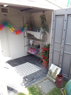 an outdoor storage shed with potted plants and other items in the back door area