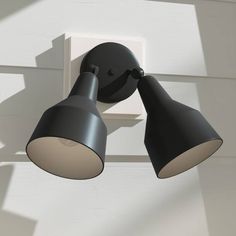 two black lamps are on the side of a white wall and one light is off