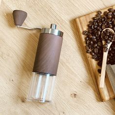 a wooden cutting board topped with coffee beans next to a grinder