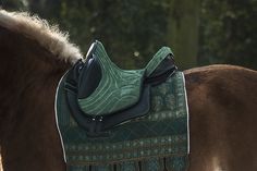 a brown horse with a green saddle on it's back