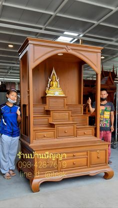 two children standing in front of a wooden cabinet with drawers and shelves on the sides