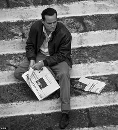 a man sitting on steps reading a newspaper