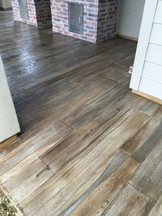 an empty room with wood flooring and brick wall in the background, next to a door